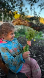 criança segurando caules verdes suja de lama