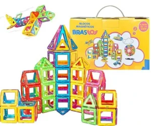 um castelo de brinquedo montado com peças magneticas coloridas e um avião montado com essas peças no canto superior esquerdo. No canto superior direito vemos a caixa do brinquedo amarela com a marca em destaque "Brastoy"