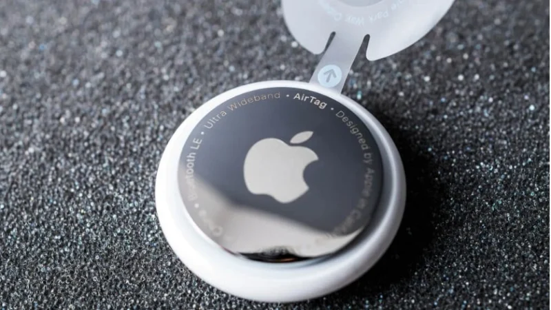 Dispositivo AirTag da Apple utilizado para rastrear crianças, garantindo maior segurança. Sob fundo de asfalto preto.